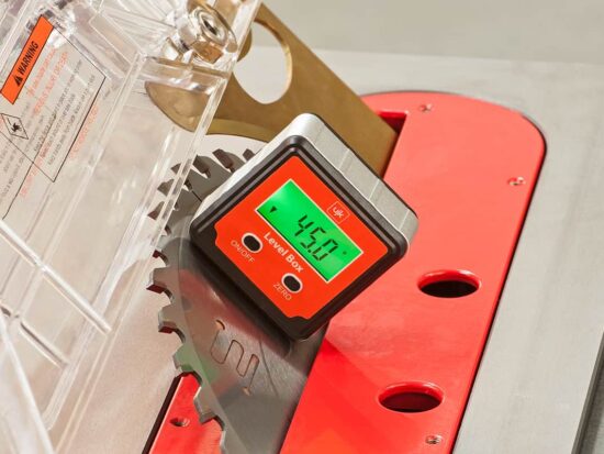 A close-up of a digital laser level attachment mounted on a red and silver table saw, showing a green LCD screen with the reading '45.0' and labels 'Laser Level' and 'IN'.