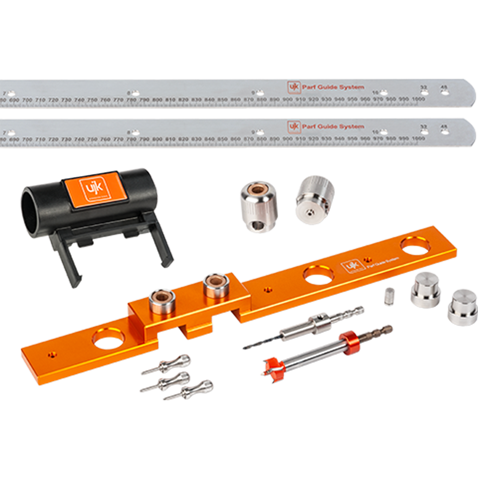 A Parf Guide System tool kit featuring an orange anodized aluminum base bar, two silver metal guide rails with printed measurements, a black plastic mounting bracket with an orange logo, several silver metal collars, pins, and a drill bit, all arranged on a white background.