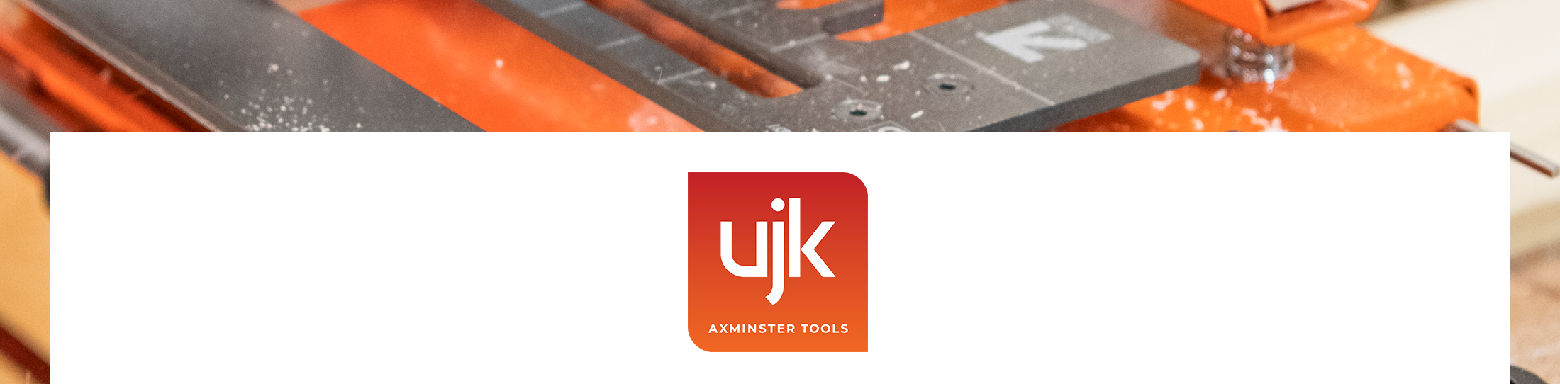 A close-up of an orange and grey woodworking tool with a white banner overlay in the centre featuring the red and orange UJK logo.